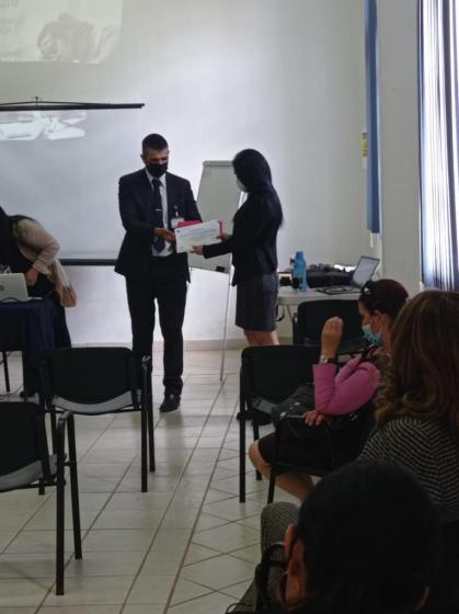 Dos personas paradas sosteniendo un diploma.