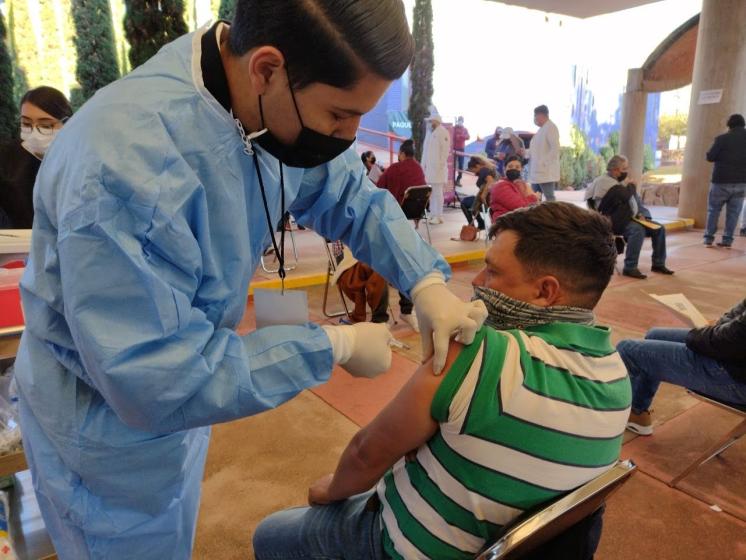 Integrante del programa de vacunación de refuerzo a personal docente aplicando una vacuna.