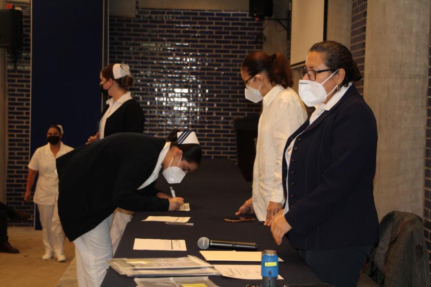 Estudiante de enfermería firmando ante autoridades.