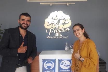 Dos personas sonriendo mientras miran a la cámara, tienen sus pulgares arriba. En el fondo un emblema que se lee "Venvivir" "Mereces estar bien".