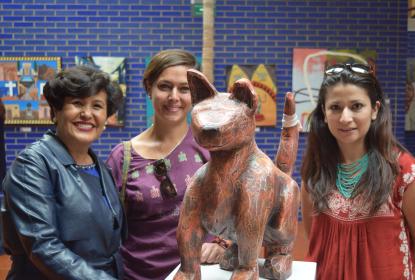 Tres mujeres viendo a la cámara, frente a ellas una obra.